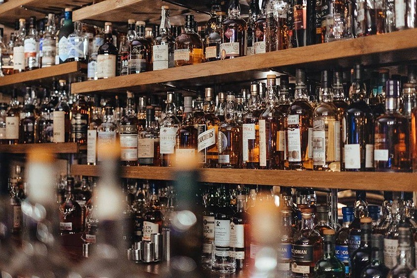 Fulla hyllor med stora flaskor alkohol på en bar eller spritbutik