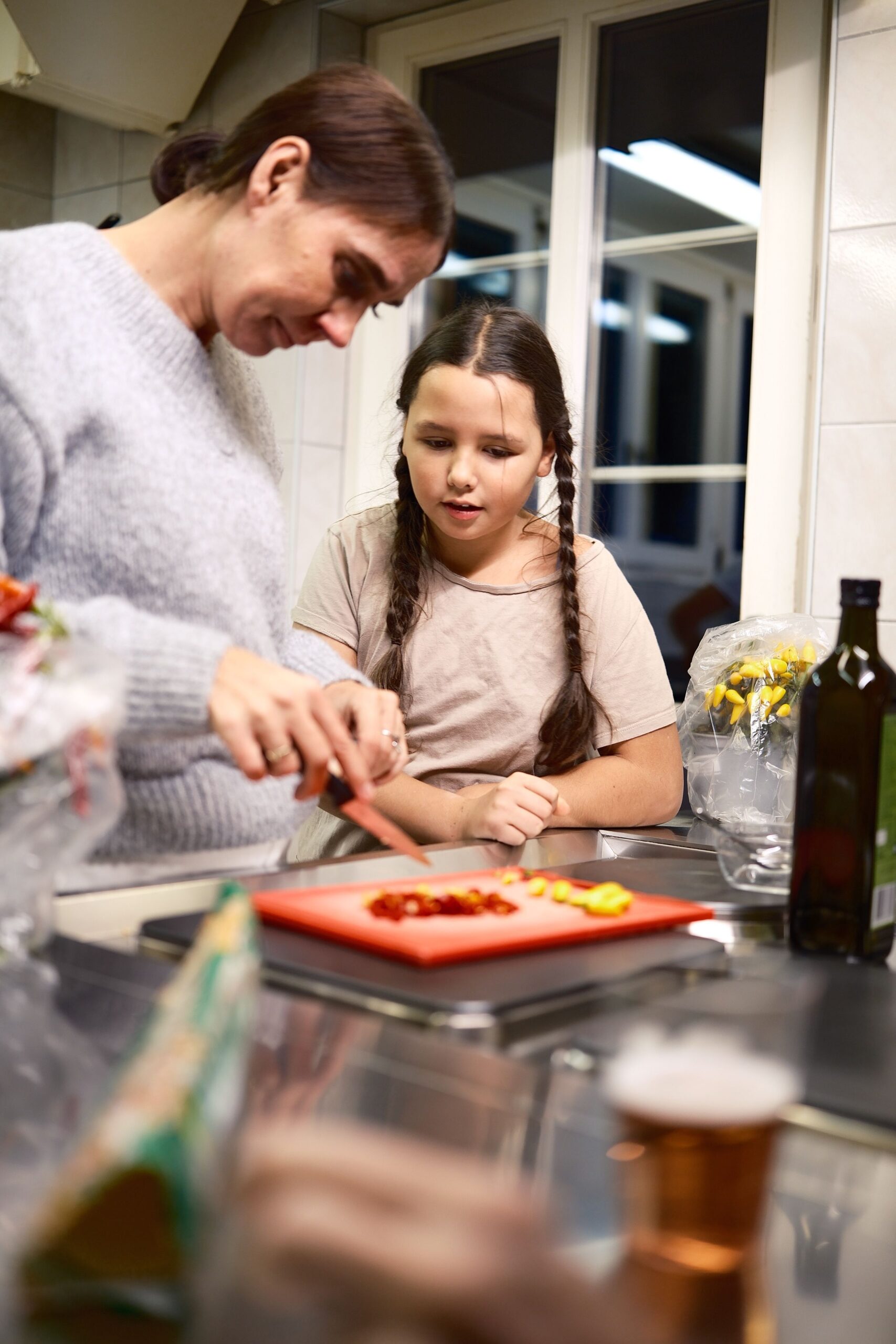 A mother and daughter chopping vegetables together in a cozy kitchen setting.