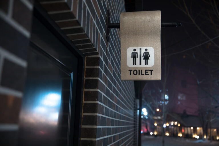 Toalettskylt för män och kvinnor på en tegelvägg med oskarp bakgrund